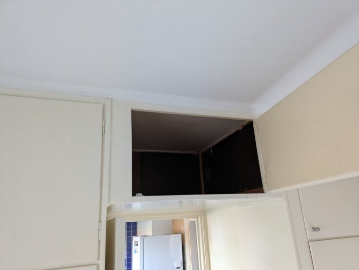 Öppet skåp i garderobshörn med synligt eluttag högst upp, svårtillgängligt på grund av placeringen.