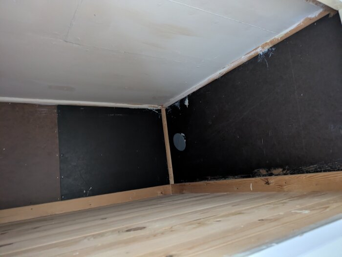 Garderobshörn med träsida och mörk panel, visar placering av en dosa för elinstallation.