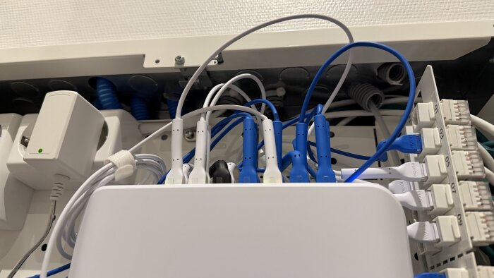 Nätverkscentral med kablar och enheter anslutna, visar ledningar från elcentralen till nätverksutrustningen.