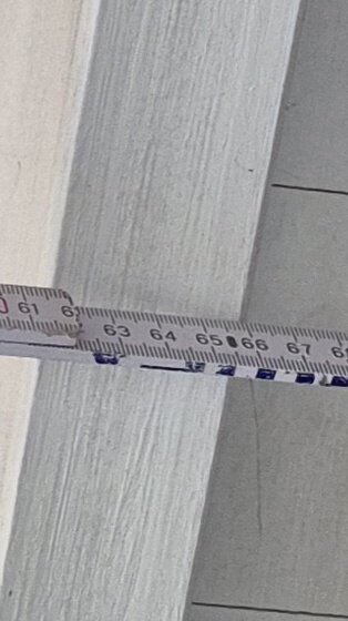 Mätband visar oregelbundna mått mellan två brädor när ströläkt spikas fast.