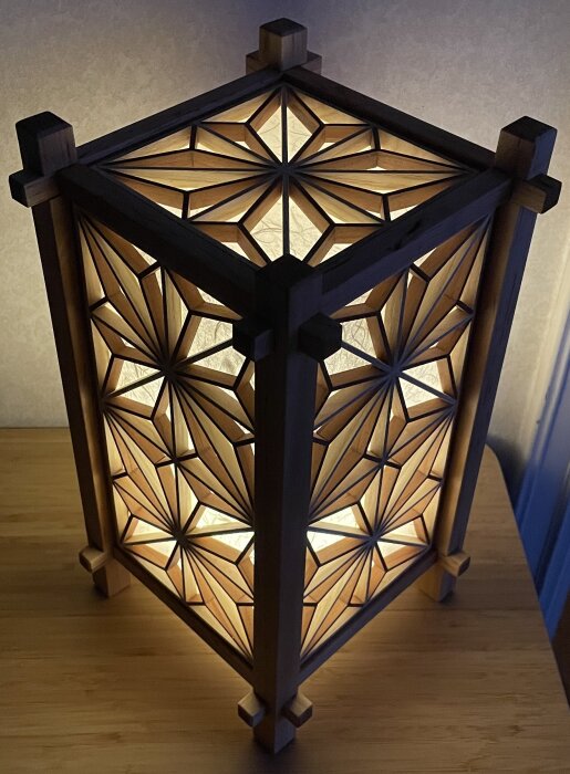 Kumiko-inspirerad lykta med geometriskt trämönster, inuti en batteridriven nattlampa som sprider varmt ljus.