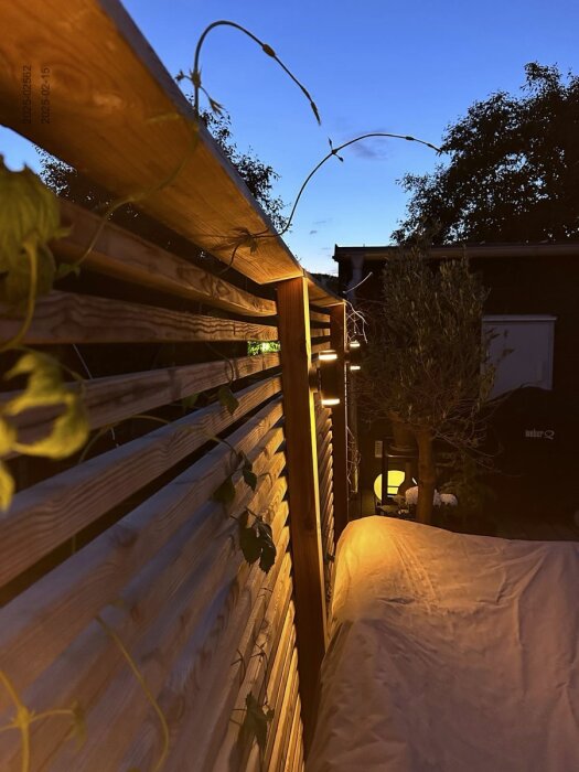 Ny altan med träinsynsskydd och belysning i skymningen.