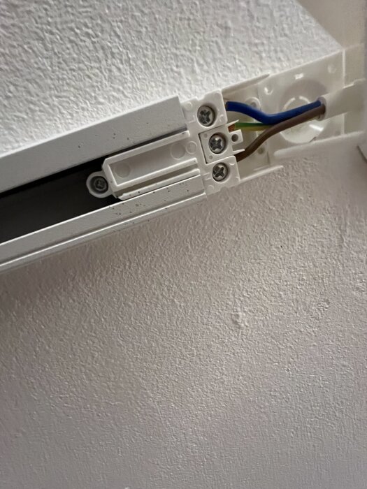 Kontaktpunkt för elspottar, med ledningar kopplade i en vit takskena. Saknar monterade lampor.