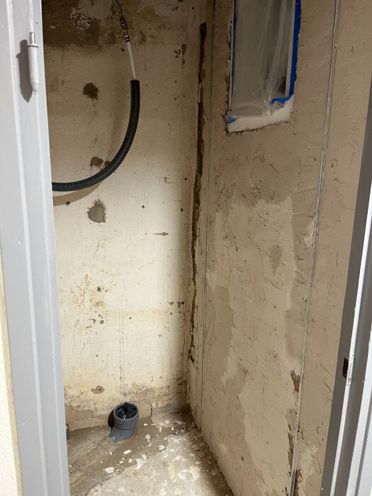 Råvägg i renoveringsprojekt med synliga rör och slätad yta, förberedd för puts och kommande tapetläggning samt installation av eldrivet element.