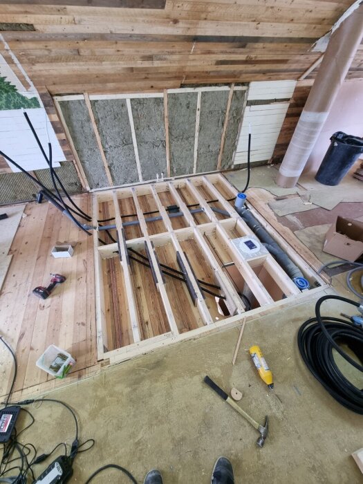 Badrumsrenovering med nytt bjälklag, avskalade väggar och verktyg på golvet.