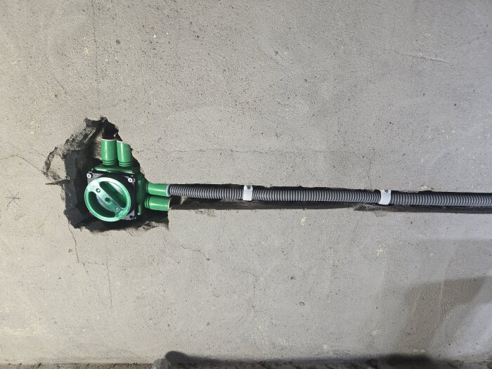 Vägg med monterad elkopplingsdosa och anslutna flexrör, fastsatta med clips och plugg.