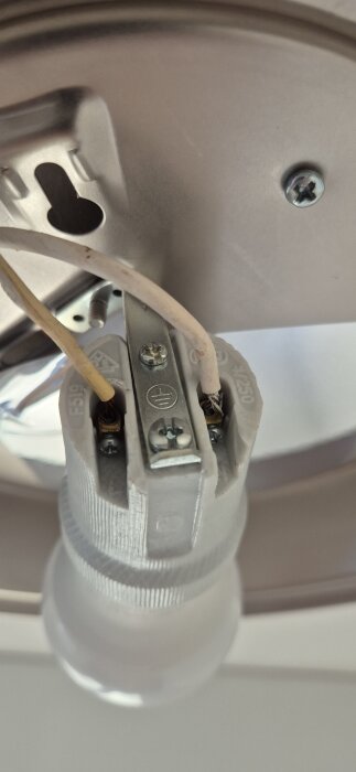 Bild på taklampa med exponerade kablar i kontakt, där sladdarna går in direkt från taket, osäkerhet kring vilka kablar som är fas och nolla.