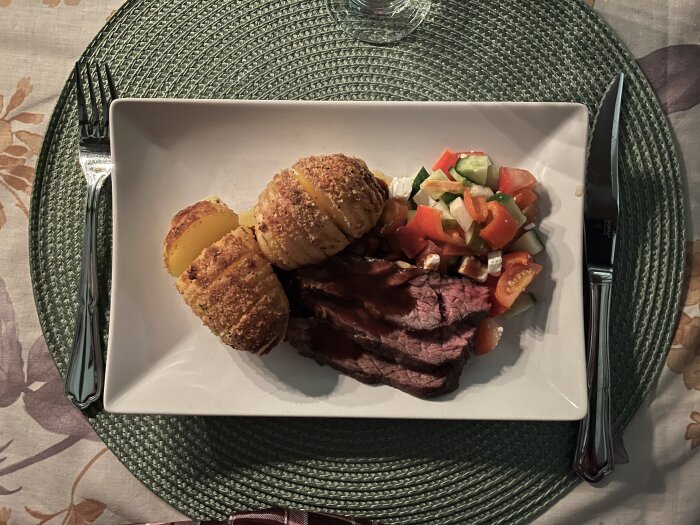 Vitlöksmarinerad flankstek med rödvinssås, hasselbackspotatis och grönsakssallad på tallrik.