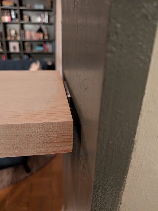 Trähylla med synlig fog mellan hyllplan och vägg, visar en smal springa runt 5 mm bred.