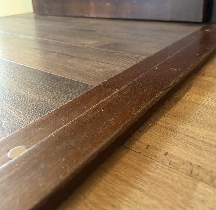 Tröskel i trä som robotdammsugare fastnar på, i en villa från 1979. Golv av olika träslag på varsin sida av tröskeln.