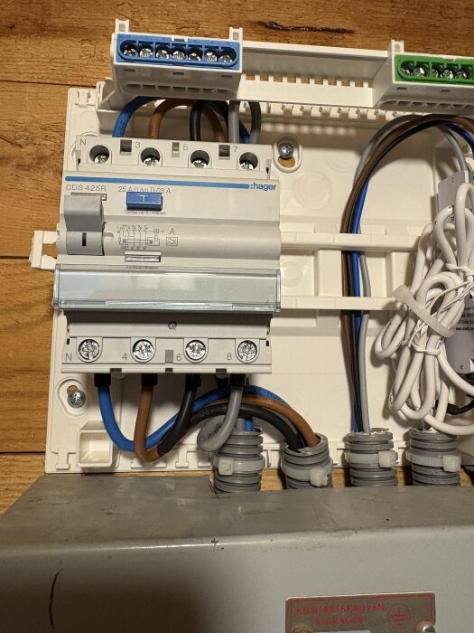 Bild på elcentral med jordfelsbrytare av märket Hager, visar anslutna kablar och kopplingar på en trätavla.