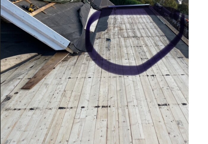 Ovanifrån bild av ett tak med öppnad sektion. Råsponten syns tydligt med en mörkfärgad del i mitten där två tak möts. Markerat område i lila.