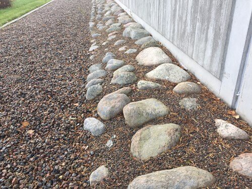 Kullersten framför husgrund med grusgång.