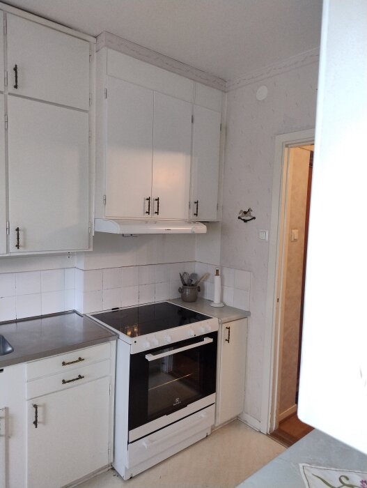 Gammalt vitt kök med ugn och fläkt, väggklack syns i hörnet. Möjliga renoveringslösningar: 50-talsstil eller modernt IKEA-kök.