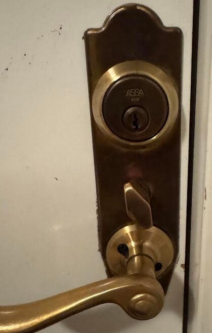 Bild på ett dörrhandtag med ett mässingspläterat ASSA 2000-lås från 1999.