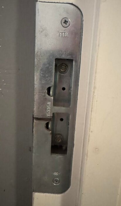 Närbild av ett dörrbleck märkt ASSA och siffrorna 353358.