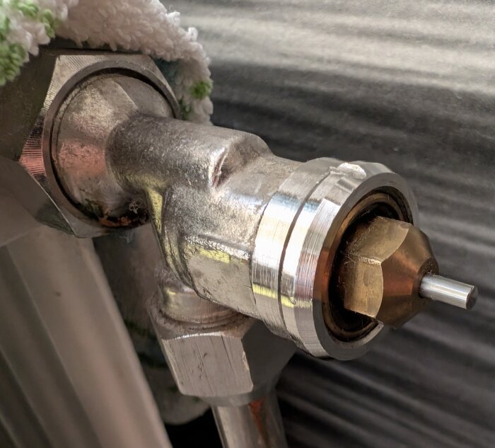 Oidentifierad radiatorventil med en adapter som inte passar korrekt; ventilen har en tydlig metallisk yta och en utskjutande del.