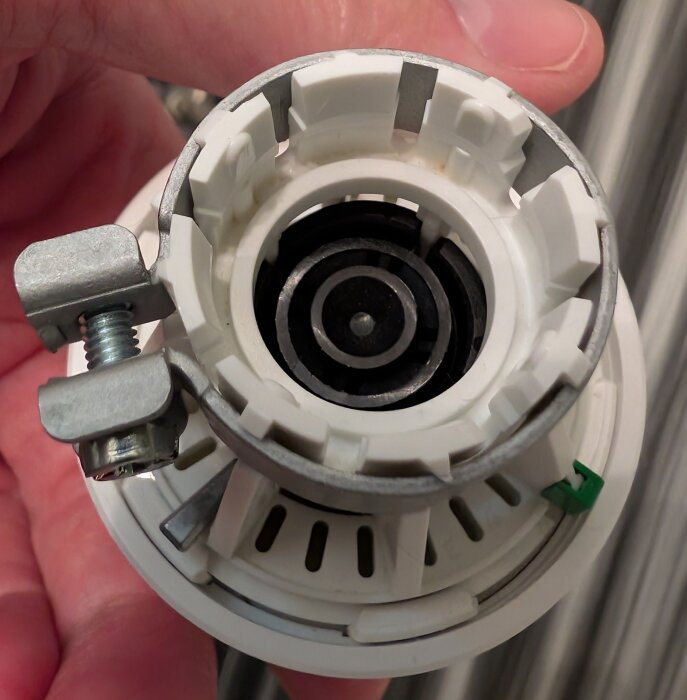 Närbild av en Danfoss-termostat monterad på en radiatorventil. En skruv och klämma syns tydligt i vänstra kanten av bilden.