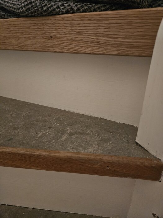 Nya trappnosen i ek med bredare överhäng installerad ovanpå gamla trappsteg i en renovering.