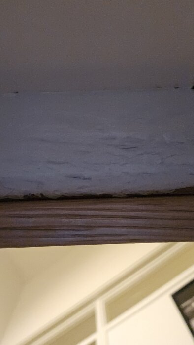 Närbild av en ny bredare trappnos med ett litet överhäng, mot en vit vägg, i ett renoveringsprojekt.