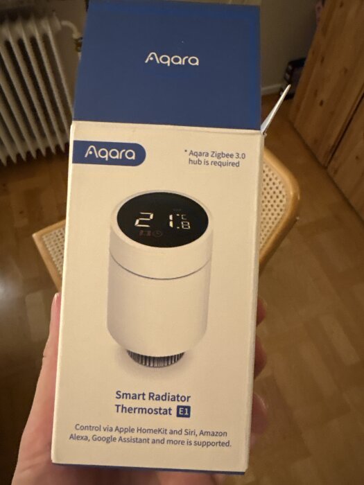 Förpackning för Aqara Smart Radiator Thermostat E1 med en hand som håller lådan.