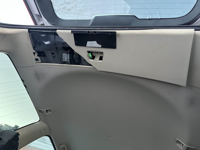 Interiören på bakluckan av en Volvo XC70, med delvis demonterad panel där kablar och inre struktur syns.
