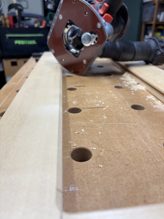 Handhållen överfräs på arbetsbänk med träspån runt omkring.