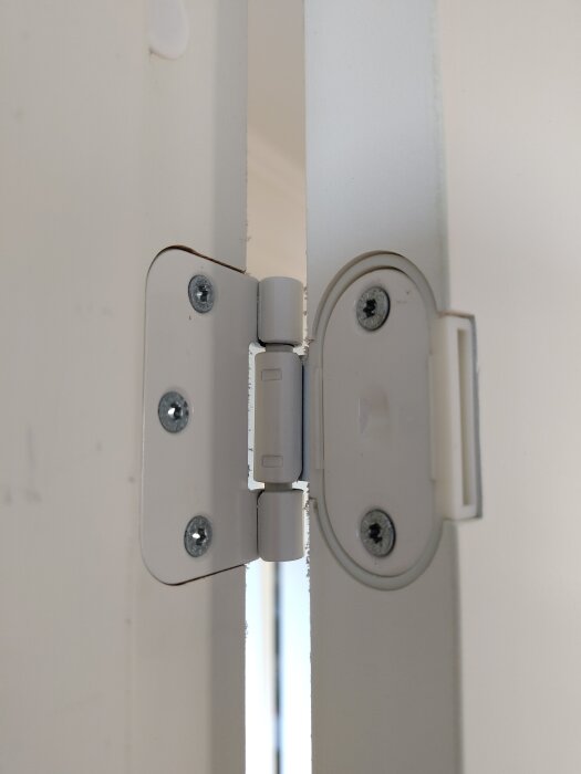 Närbild av ett gångjärn på en vit innerdörr från Swedoor, med en springa mellan dörr och karm.