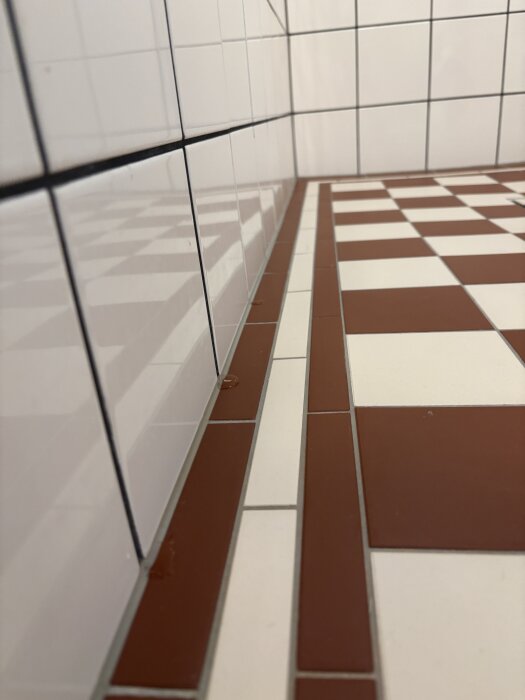 Victorian golvplattor i badrum med vatten som ligger på plattorna nära vägg, visar lutning och tätning av kakel.