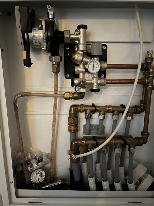 Cirkulationspump och rörsystem i ett hus, med en oinkopplad pump och saknad hon-kontakt, relaterat till problem med elementen på övervåningen.