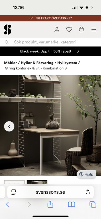 Stringhylla med arbetsyta, brun ek och vit metall, omgiven av gröna växter och dekorationer.