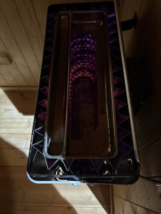 Aggregat som lyser lila inuti, monterat i ett träbeklätt rum.