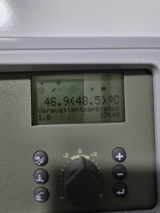 Digital display på värmesystem som visar varmvatten temperatur 46.9°C och mål 48.5°C. Reglagets inställningar synliga nedanför.