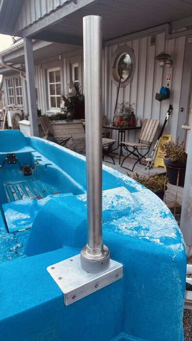 Rostfritt räcke monterat på en blå trampbåt med aluminiumfäste, omgiven av en veranda med utemöbler och dekorationer.