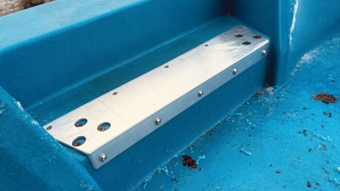 Förstärkning av aluminiumprofil med skruvar på en blå trampbåt.