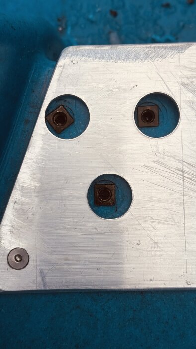 Aluminiumprofil med tre borrade hål och skruvar, monterad på blå båt som del av förstärkning för trampbåtens rostfria räcken.