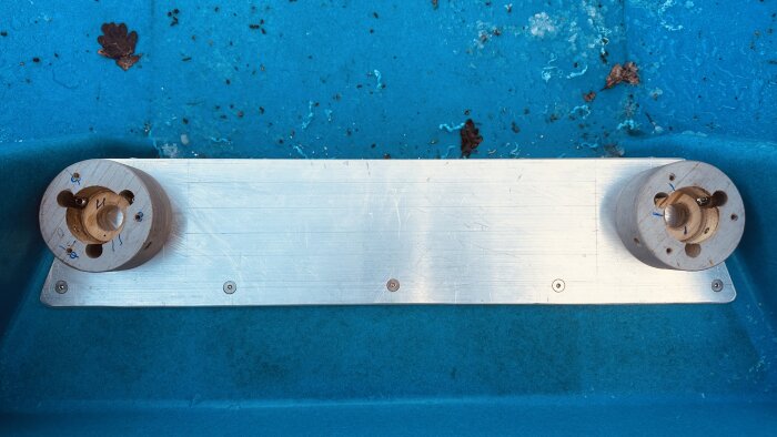 Rostfri aluminiumprofil med hål på en blå båt; delar av förstärkt fästsystem syns.