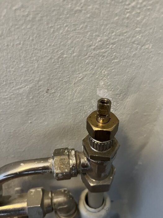 Gammal golvtermostat med metallrör och kopplingar, möjligen från ett hus byggt 1989.