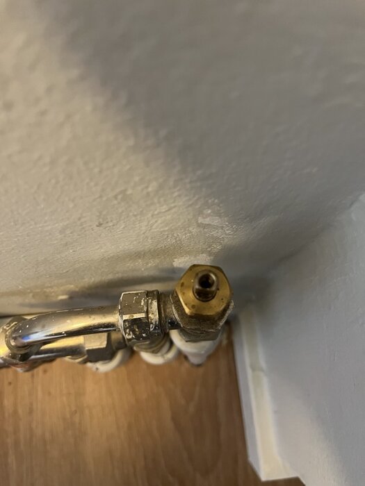 Gammal golvtermostat från 1989 med metalldelar monterad inomhus mot en vägg.