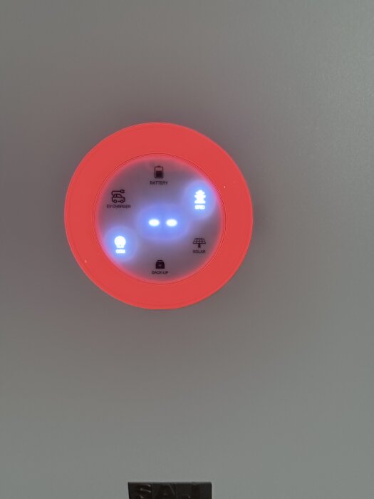 En elektronisk enhet med en röd lysande ring och flera indikatorlampor, inklusive "COM" blinkande och "GRID" solid.