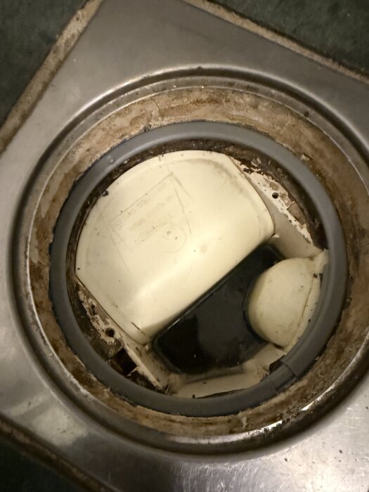 Trasig klämring i diskhon med smuts och en ny klämring som installerats för att lösa problemet.