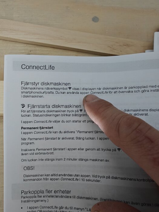 Man pekar på användarmanual för diskmaskinens WiFi-anslutning med instruktioner om att använda appen ConnectLife.