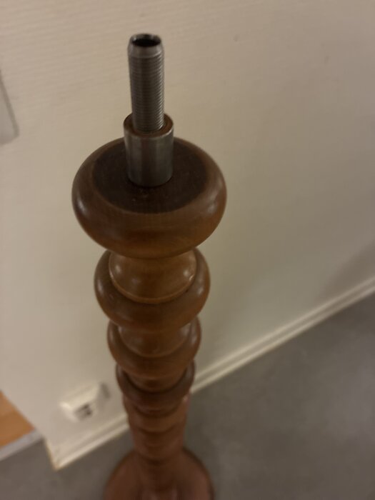 Gammal golvlampa utan skärm, med trästomme och metallgänga på toppen i behov av ny kabel.