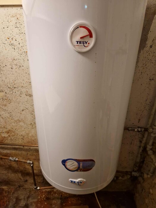 Vattenvärmare i ett rum, ansluten till rör. Märkt med "TESY". Diskussion om droppande problem och elektrisk avstängning.
