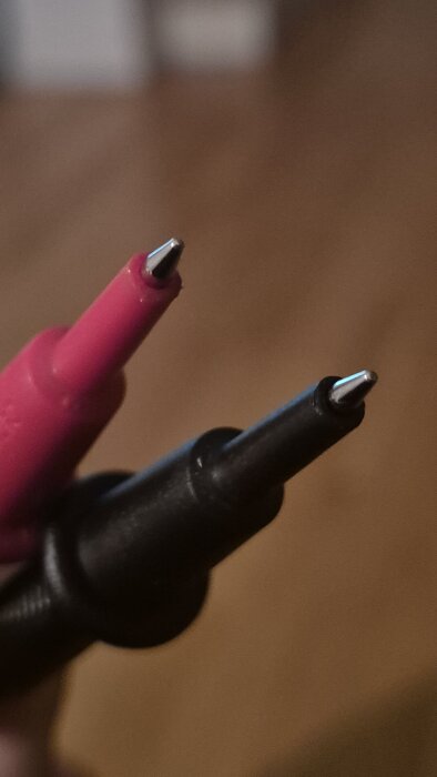 Två spetsiga mätprober, en röd och en svart, för multimeter används för elektriska mätningar.