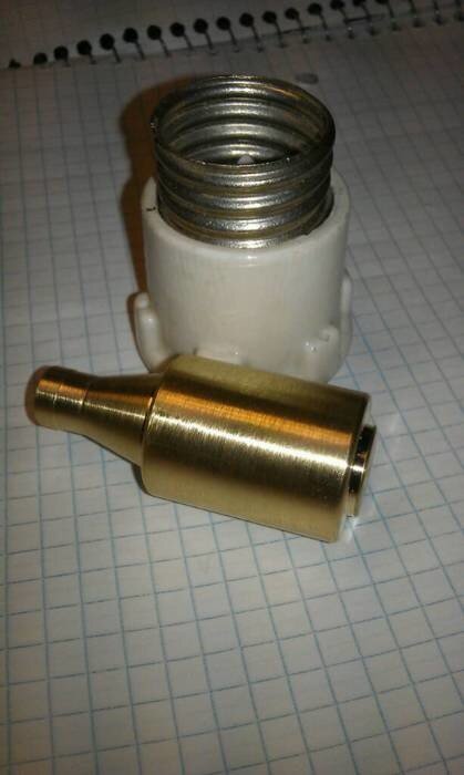 En mässingsadapter och en vit koppling på ett rutat papper.