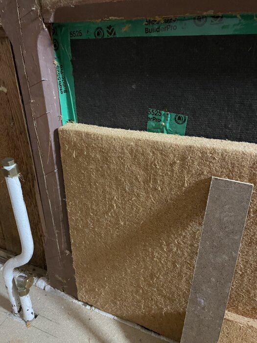 Väggkonstruktion med asfaboard, isolering och rör i ett renoveringsprojekt.