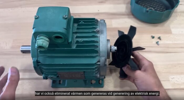 En person monterar en kylfläkt på en elektrisk motor på ett bord.