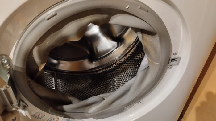 Öppen tvättmaskinstrumma med sliten gummitätning, diskussion om ansvar och underhåll av maskin som är 10 år gammal.