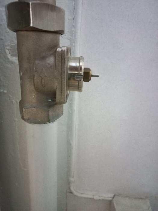 Radiatorrör med avskuren del av termostatventil utan termostat monterad, mot vit bakgrund.